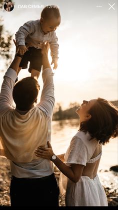 a man holding a baby up in the air while standing next to two other people