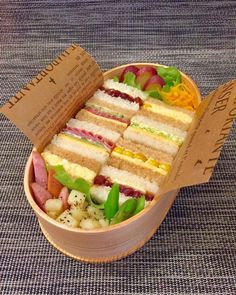 a wooden box filled with lots of different types of sandwiches on top of a table