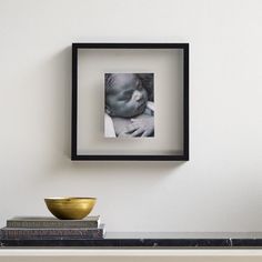 a black and white photo hanging on the wall above a shelf with two books next to it