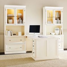 a desk with a computer on top of it next to a bookcase and cabinets