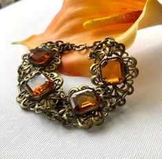 Beautiful antique Art Deco era bracelet. Circa 1920s - 1930s or so.  Rich warm deep yellow-orange citrine-like glass faceted stones - so perfect for the rich Autumn colors of Fall. Fancy scroll links with etched designs on the connecting links. What a neat detail! Very Czech-looking although I didn't see any markings. Likely brass metal as most of these types of bracelets were during this time. In very good used antique condition. Light surface wear and normal aged tarnish and patina. Rich dark warm antiqued gold hue to the metal. A little verdigris in a couple of tiny spots. I have not tried to clean or polish in any way.  Measures about 7" long in total length. See all photos for details, scale, and proportion.  Thanks for remembering to always read item descriptions in the listings.  Se Adjustable Vintage Amber Jewelry, Collectible Vintage Amber Jewelry, Vintage Orange Bracelets As Gifts, Retro Orange Jewelry For Formal Events, Retro Orange Jewelry For Formal Occasions, Orange Victorian Jewelry For Formal Occasions, Yellow Vintage Bracelet As Gift, Antique Orange Jewelry For Wedding, Types Of Bracelets