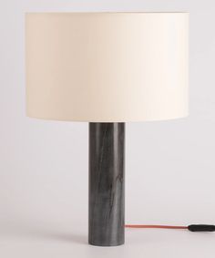 a table lamp with a white shade on it and a black cord attached to the base