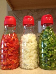 three bottles filled with different types of vegetables on top of a counter next to each other