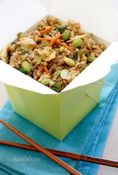 a green box filled with rice and veggies on top of a blue napkin