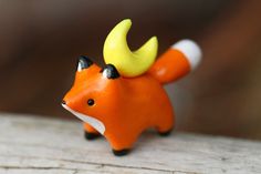 an orange toy with a yellow horn on it's head sitting on a piece of wood