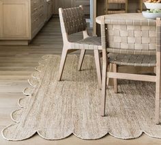 a table with two chairs and a bowl of fruit on it next to an area rug