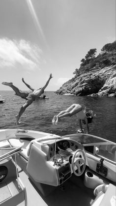 a man diving into the water from a boat in front of another person on a body of water