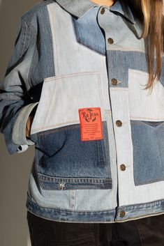 a woman wearing a jean jacket with an orange tag on it