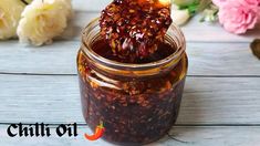 a jar filled with jam sitting on top of a wooden table next to pink flowers