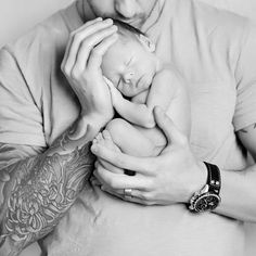 a man holding a baby in his arms while wearing a watch on his left wrist