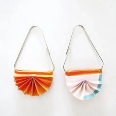 pair of earrings made out of folded paper on white background with orange, blue and pink colors