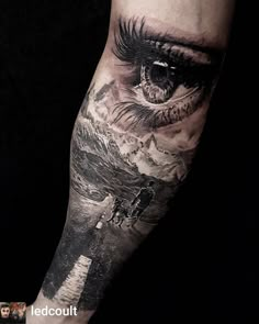 a man's arm with an eye and mountain scene on the inside of it