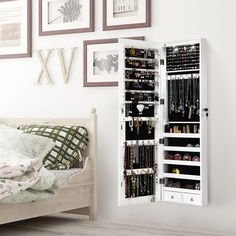 a white jewelry cabinet sitting next to a bed