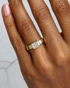 a woman's hand with a yellow gold ring on it and a diamond in the middle