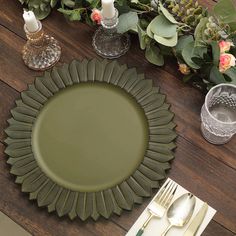 a green plate sitting on top of a wooden table next to silverware and flowers