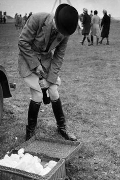 a man bending over to pick up something out of the ground with his hat on