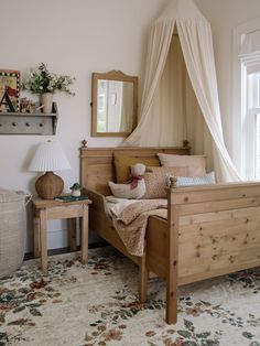 a bedroom with a canopy bed and pillows on the floor in front of a window