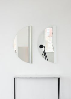 two mirrors on the wall above a table with a tripod in front of it