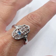 *  Sterling Silver Hamsa Tiny Blue Sapphire CZ Ring, Hand of God Ring, Religious Ring, Hamsa Promise Ring, Silver Ring, Statement Ring, Love Ring, Boho Ring, Eye Ring, 925 Stamped *  Hamsa is primarily used to protect its owner from the Ayin Ha'ra also known as The Evil Eye Protective talisman that brings good fortune, health and happiness *  Perfect gift idea for any occasion: birthday, anniversary, engagement, graduation, bridesmaid, Mother's Day, Valentine's Day, Christmas, promise. *  Your p Promise Ring Silver, Protective Talisman, Hand Of God, Blue Sapphire Ring, Ring Hand, Eye Ring, Boho Ring, Cz Ring, Blue Band