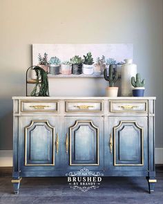 an old dresser is painted blue with gold trim and has potted plants on top