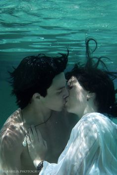 a man and woman kissing under the water