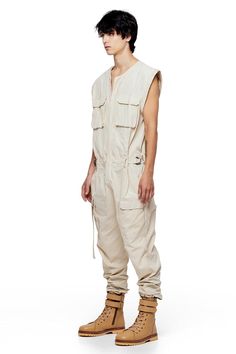 Jonny Cota takes on the summer suit with this season's Sleeveless Canvas Jumpsuit, crafted from soft baby canvas with cargo patch pockets and gun metal hardware detailing throughout. — Cargo patch pockets— Gun metal snaps— Zip closure at center middle— 100% baby canvas suedeSIZE + FIT— Loose, relaxed fit— Adjustable d-ring belt at waist— Model is 6’0 and wearing a size L CARE— Dry clean recommended Utility Style Sleeveless Jumpsuits And Rompers With Pockets, Summer Overalls With Cargo Pockets, Utility Cotton Jumpsuits And Rompers With Patch Pockets, Utility Cotton Jumpsuits And Rompers With Multiple Pockets, Sleeveless Cotton Utility Jumpsuits And Rompers, Utility Overalls With Cargo Pockets For Summer, Cargo Style Overall Jumpsuit For Summer, Utility Cotton Jumpsuits And Rompers In Cargo Style, Utility Cotton Jumpsuits And Rompers With Cargo Pockets