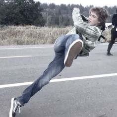 a young man doing a trick on a skateboard in the middle of an empty parking lot