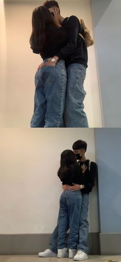 two people are hugging each other in front of a white wall and another person is standing behind them