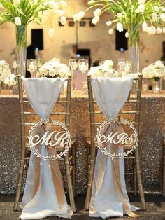 the chairs are decorated with white flowers and monogrammed sashes