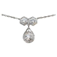 Incredible vintage diamond necklace bursting with Old World charm. This gorgeous piece boasts a simple yet elegant design, elevated by the intricate filigree detailing that really enhance the stunning Old European cut diamonds. This necklace is a true treasure. This beautiful drop necklace features 2 Old European cut natural diamonds (F-G in color, I1 in clarity) 6 prong set and arranged in hexagon shaped settings with delicate filigree borders. Dangling from the 2 stones is hinged teardrop shaped filigree drop featuring a single .85 carat Old European cut diamond (I / SI1) also surrounded by a hexagon setting. The 14 karat white gold setting really enhances the white brilliance of the stones, making this piece truly sparkle. The delicate chain is also made of 14 karat white gold and measu Exquisite Platinum Necklace With Single Cut Diamonds, Exquisite Diamond Necklace With Intricate Design, Classic Diamond White Necklace With 17 Jewels, Antique White Gold Necklace With Diamond Accents, Antique White Gold Necklace With Intricate Design, Exquisite Solitaire Necklace With Diamond Accents, Antique Round Necklace With Diamond Accents, Elegant White Gold Filigree Diamond Necklace, Elegant White Gold Diamond Necklace With Filigree