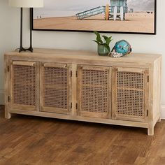 a wooden sideboard sitting on top of a hard wood floor next to a painting