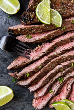 sliced flank steak with limes on the side and a fork in front of it