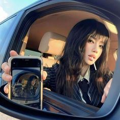 a woman taking a selfie in the back seat of a car with her cell phone