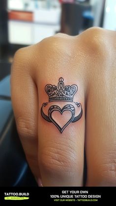 a woman's tattoo with a heart and crown on her finger