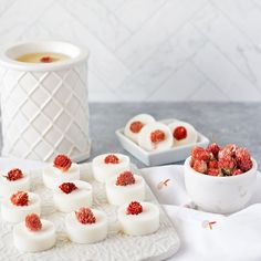 small desserts with raspberries on them are sitting next to a cup of tea