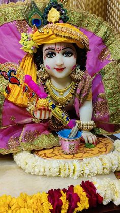 an idol is sitting on the ground with flowers around it