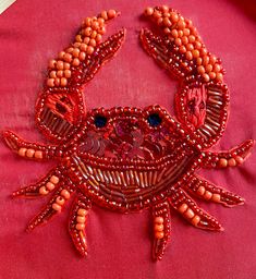 a close up of a red piece of cloth with beads on it and a crab