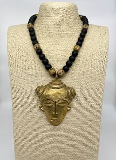 Go bold with this stunning African mask necklace for any occasion. Mask made from recycled brass items using the ancient lost wax method. Paired with onyx gemstones for durability and comfort. Necklace is approximately 27 inches long. Black Brass Amulet Jewelry, Artisan Black Brass Jewelry, Handmade Gold Onyx Necklaces, Black Brass Necklace For Festival, Black Brass Necklace For Festivals, Artisan Black Brass Necklaces, Black Brass Artisan Necklace, Artisan Black Brass Necklace, Traditional Adjustable Onyx Jewelry