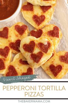 small heart shaped pizzas on top of wax paper with sauce in the bowl next to them