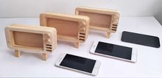 three cell phones and two wooden speakers on a table