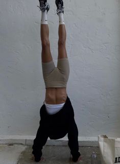 a person doing a handstand in front of a white wall