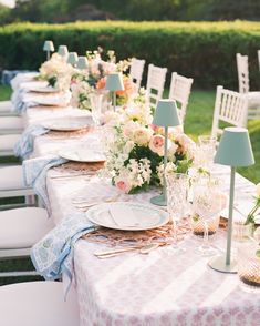 a long table set up with plates and place settings for an outdoor dinner party in the garden