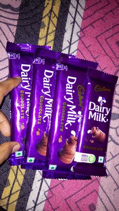 three bars of dairy milk chocolate sitting on top of a bed