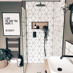 a bathroom with a white tiled shower and black and white tiles on the walls, along with a large mirror