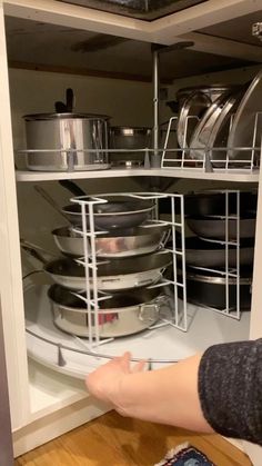 a person is reaching for pots and pans in a cabinet