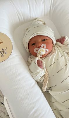 a baby laying in a crib with a pacifier