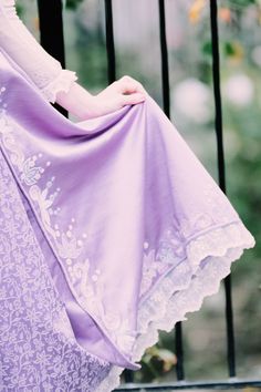 a woman in a purple dress is sitting on a bench with her hands on her hips