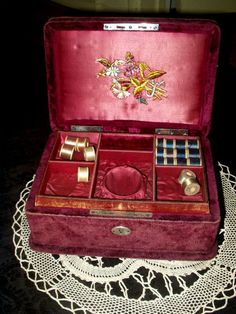 an open red velvet case with jewelry in it on a doily lace tablecloth