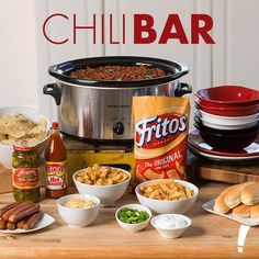 a table topped with bowls of food next to a crock pot filled with chili