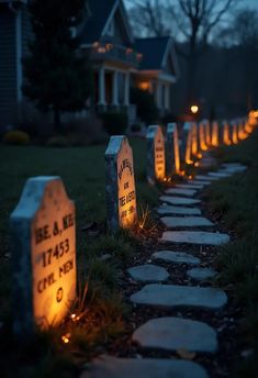 lighted tombstones in front of a house at night with the lights turned on and lit up